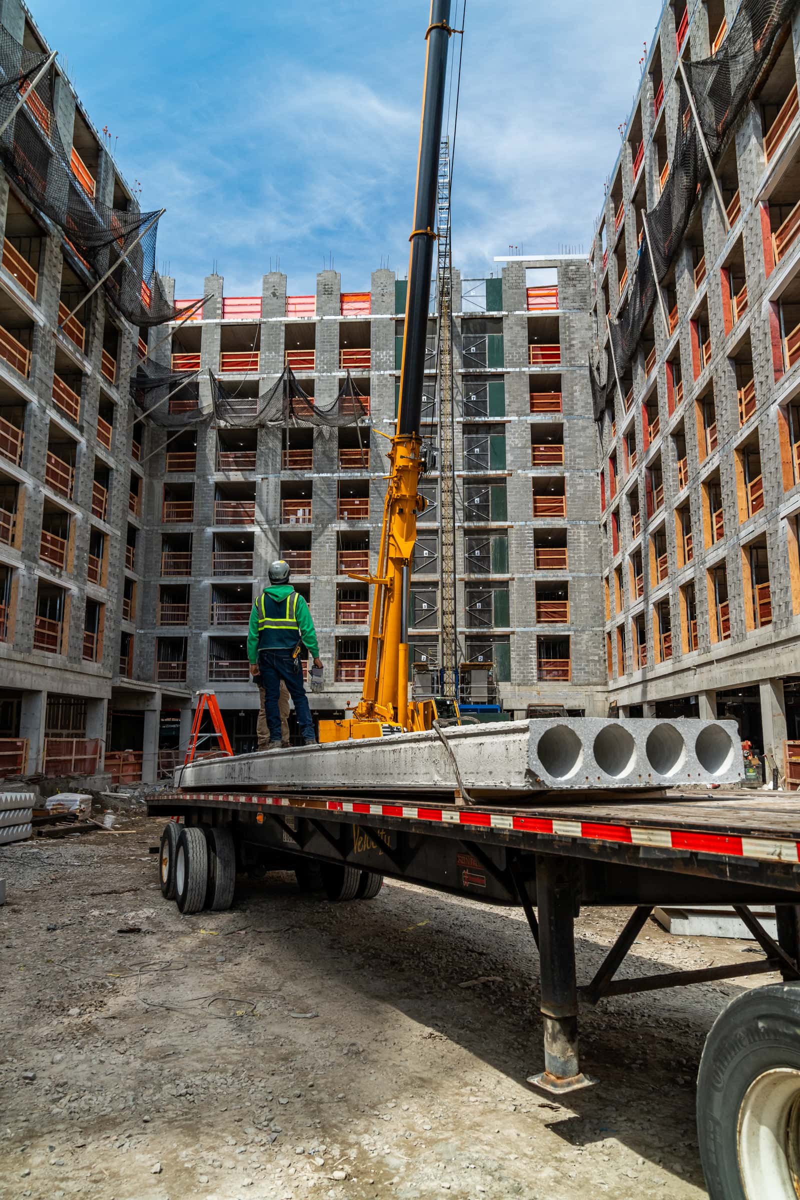 Flatbed loaded with hollow-core planks between two buildings under construction