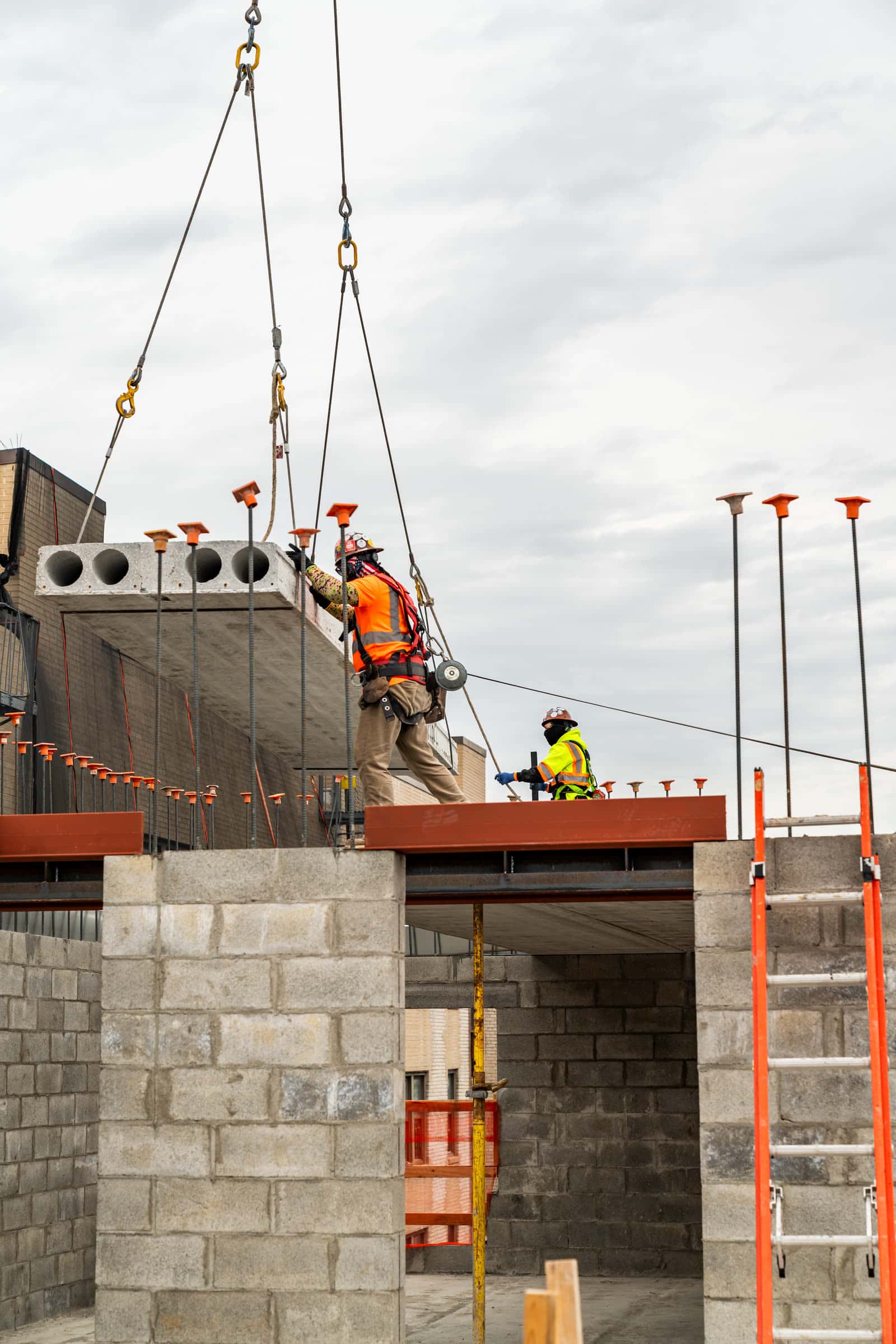 Crew setting a hollow-core plank at a roof edge