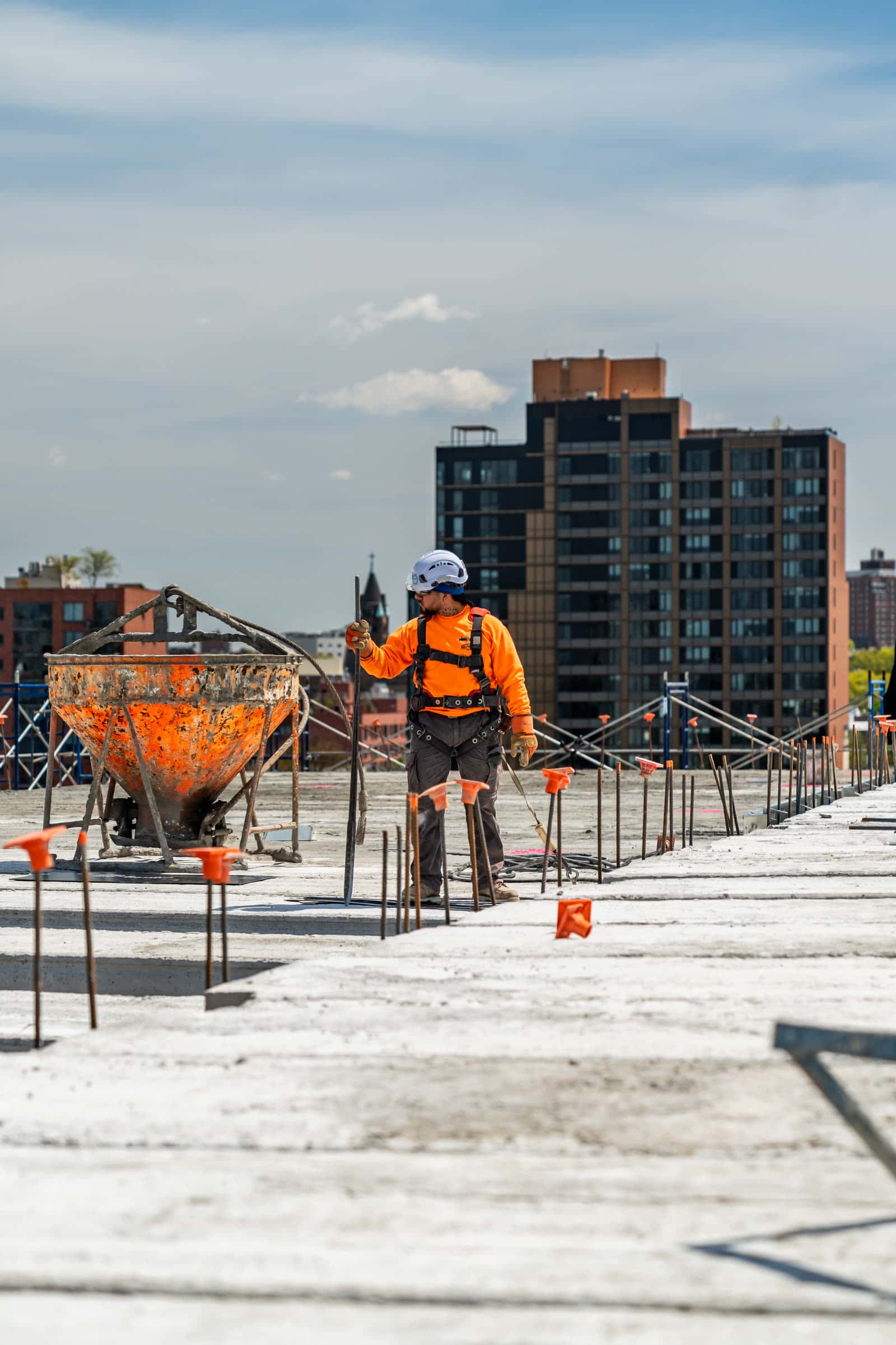 Worker with a concrete bucket on a deck with the city skyline behind