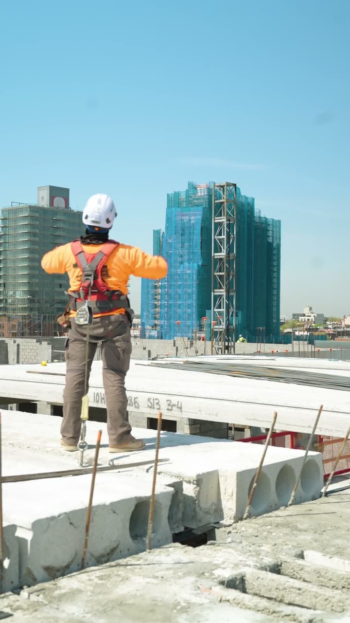 Ironworker on a precast deck with the city skyline behind